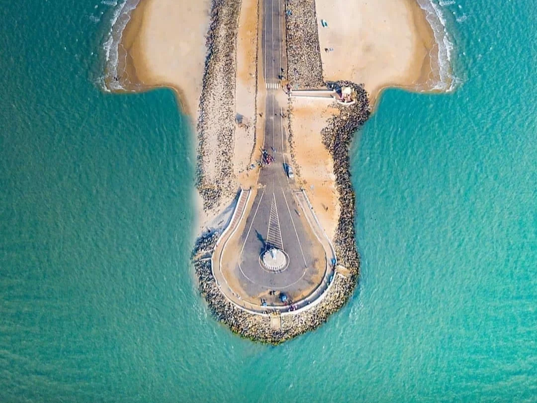 Arichal Munai Beach Dhanushkodi: Drone top-down Pamban road roundabout sandbar turquoise seas rock walls vehicles; India's lands end Ram Setu view.
