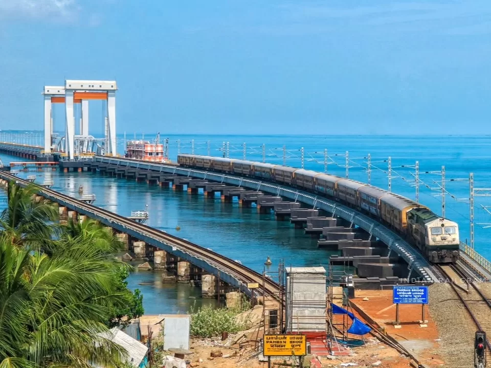 Train crossing new Pamban Bridge in Rameswaram under clear sky, featuring sea channel, pillars, perfect adventure Rameswaram tour package. 