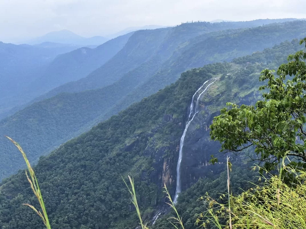 Panoramic Chellarkovil Waterfall in Thekkady during misty weather, featuring lush green Western Ghats hills and cascading falls, perfect adventure experience Thekkady tour package.