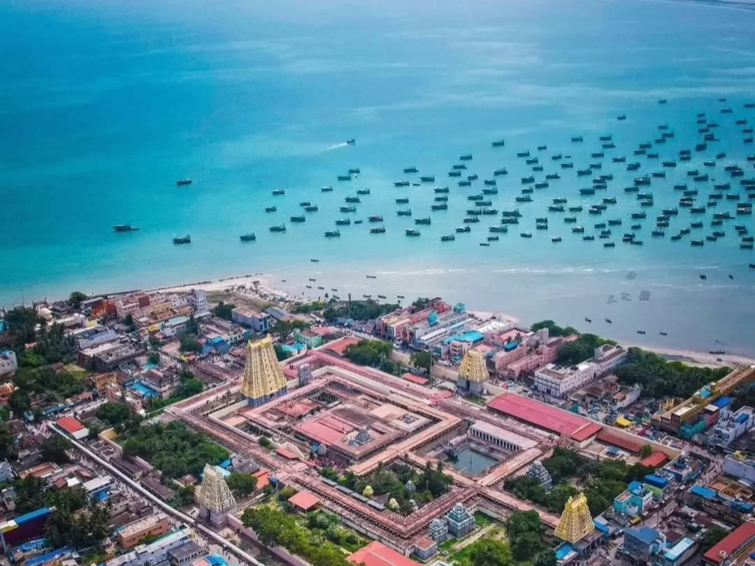 Aerial view Pamban Beach Rameshwaram Ramanathaswamy Temple Tamil Nadu India turquoise Bay Bengal fishing boats anchored sandy shoreline colorful gopuram temple complex town buildings sea horizon sunny day, perfect coastal pilgrimage scenic tour package.