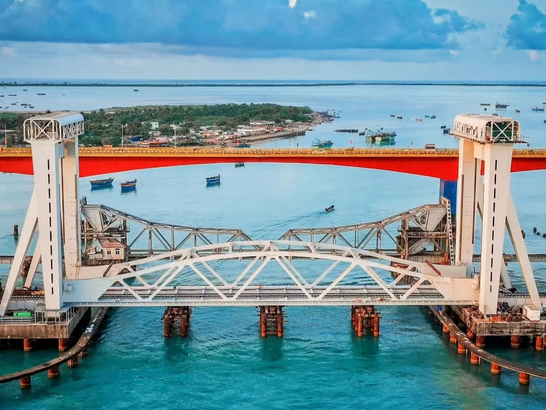 Pamban Bridge over sea at Pamban Beach in Rameswaram during evening, featuring fishing boats, distant islands, perfect adventure Rameswaram tour package.