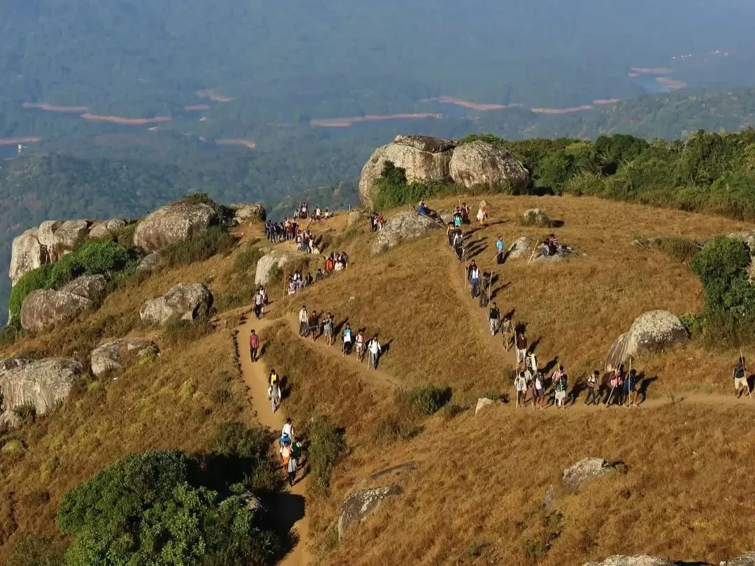 Crowds pilgrims trekking grassy rocky hilltop trails boulders lush green forested valleys distant reservoirs Velliangiri Hills Coimbatore Tamil Nadu Western Ghats, sacred seven-hill Shiva pilgrimage South Kailash spiritual trek
