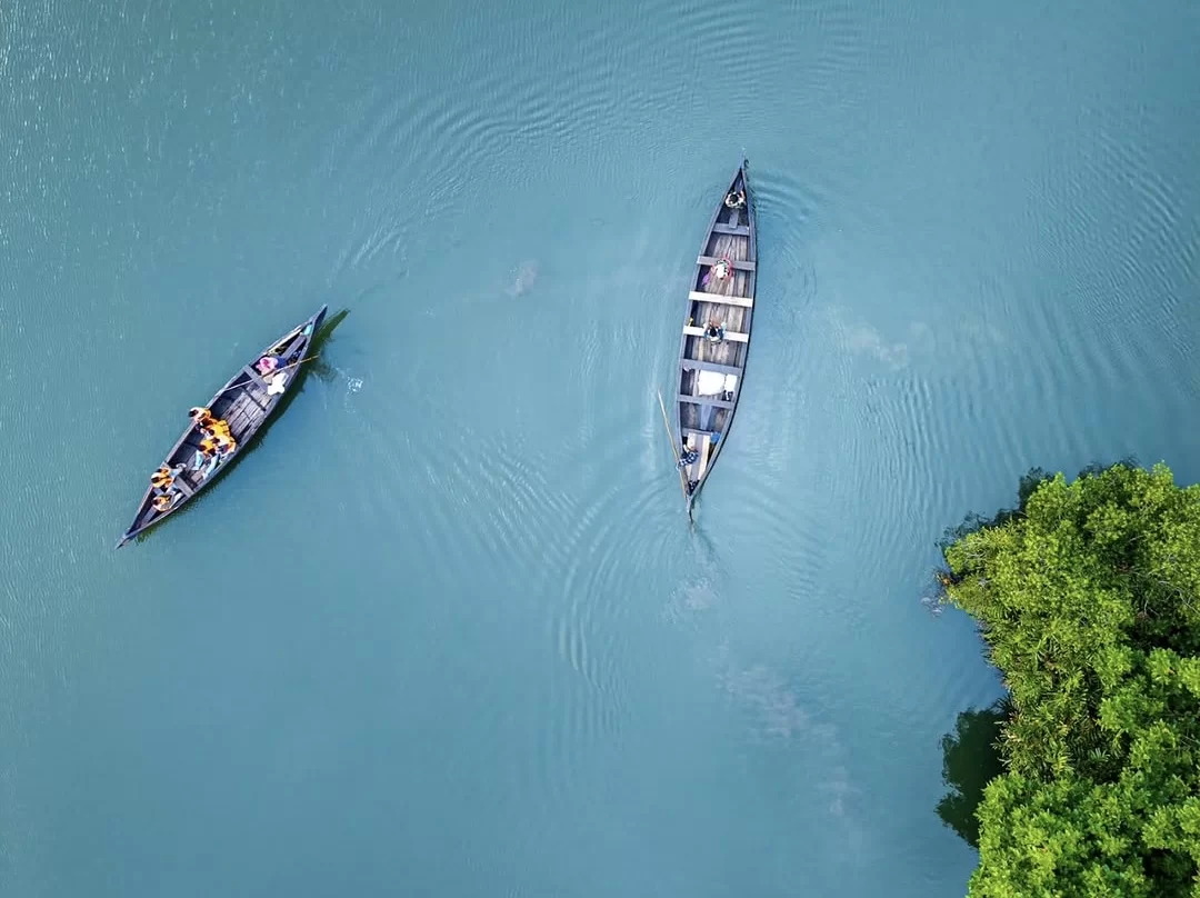 Canoe boats paddling at Munroe Island during clear skies, featuring backwaters mangroves ripples greenery, perfect romantic Kerala tour package. 