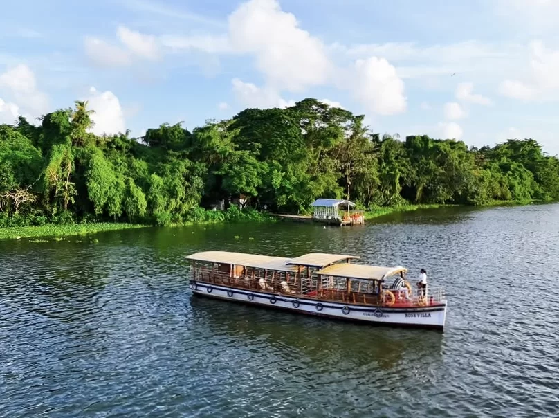 Pathiramanal Island houseboat cruise Vembanad Lake Kerala white canopy boat mangroves huts blue waters clouds, perfect backwaters eco tourism package.