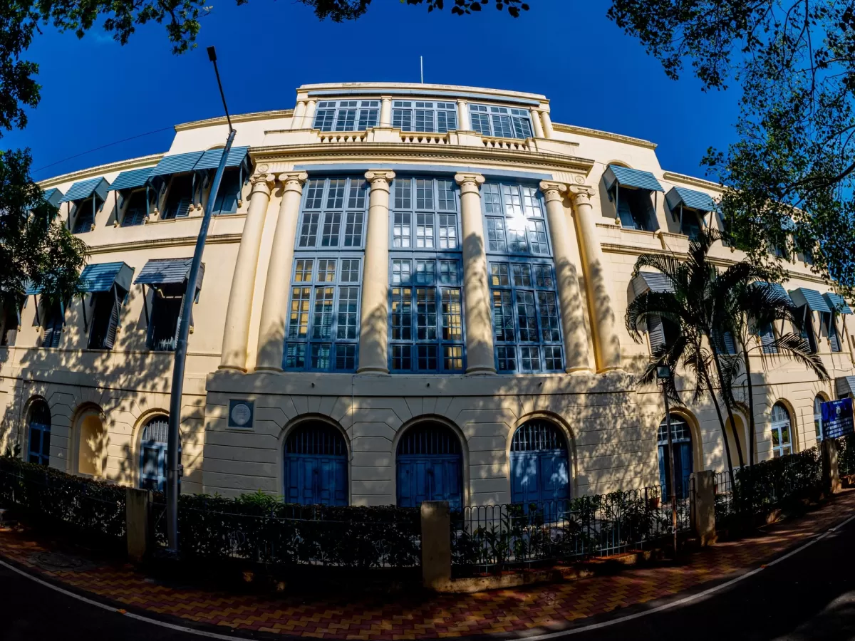 Fort St. George Museum Chennai during sunny day, featuring yellow colonial building Corinthian columns verandas palm trees, blue sky shadows, perfect historical heritage Chennai tour package.