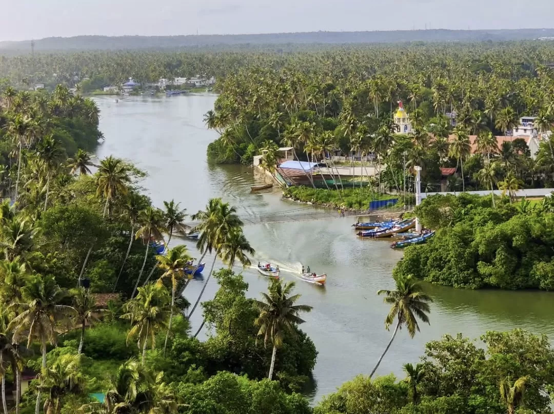 Lush aerial view of Anjuthengu Fort Kerala area with backwaters, houseboats, traditional boats, church dome and coconut groves, perfect scenic backwater heritage cruise with Varkala tour package.