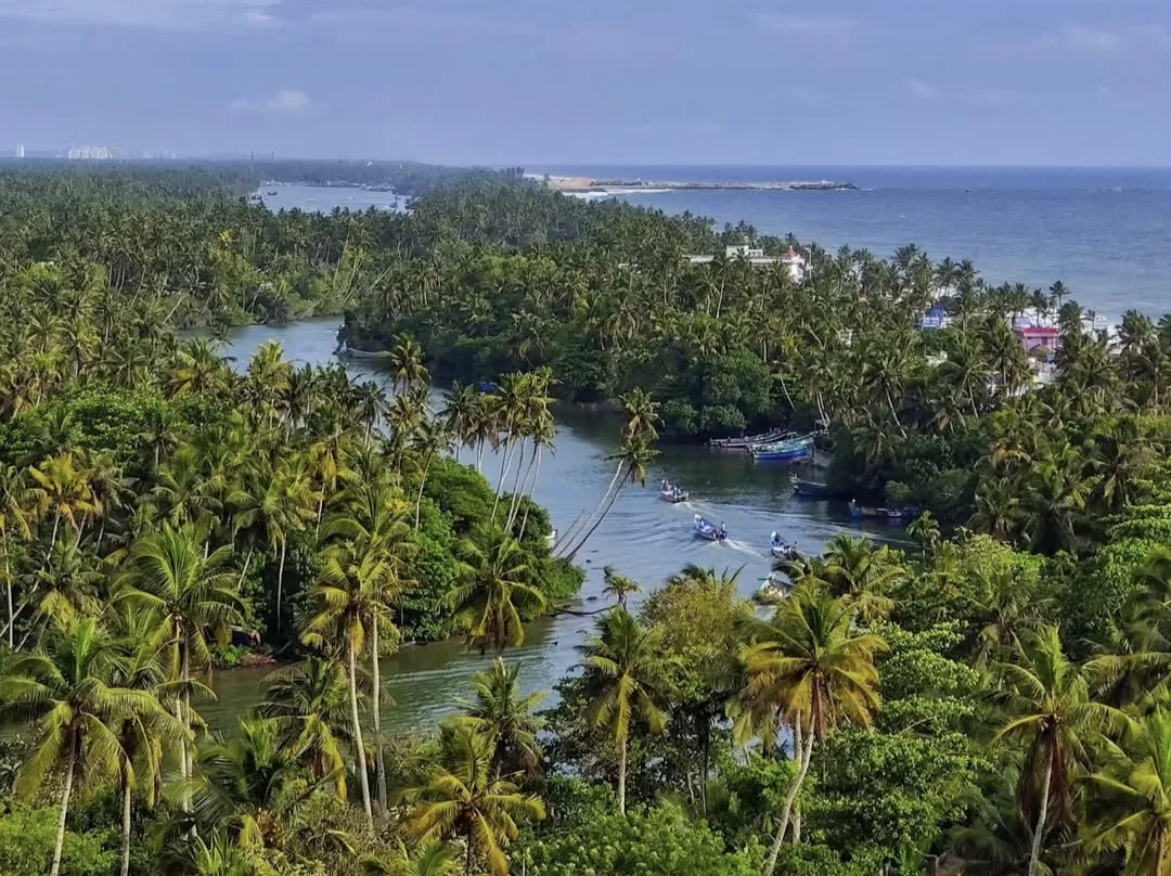 Breathtaking aerial panorama of Anjuthengu Fort Kerala region with meandering backwaters, fishing boats, dense coconut palms leading to distant Arabian Sea beach, perfect serene nature heritage getaway with Varkala tour package. 