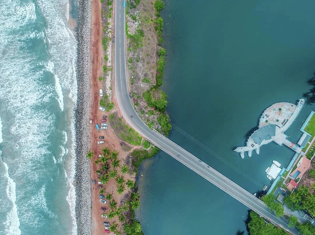 Kappil Beach Varkala Kerala aerial view sea backwater bridge divide, whale sculpture palms red road waves turquoise lake, perfect Kerala coastal confluence package. 