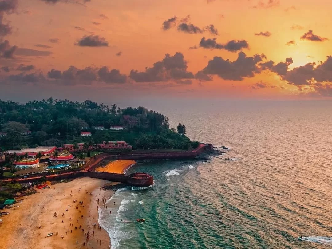 Sunset aerial of Sinquerim Beach Goa featuring Chapora Fort, golden sands, Arabian Sea waves and palm resorts, perfect romantic experience with Goa tour package. 
