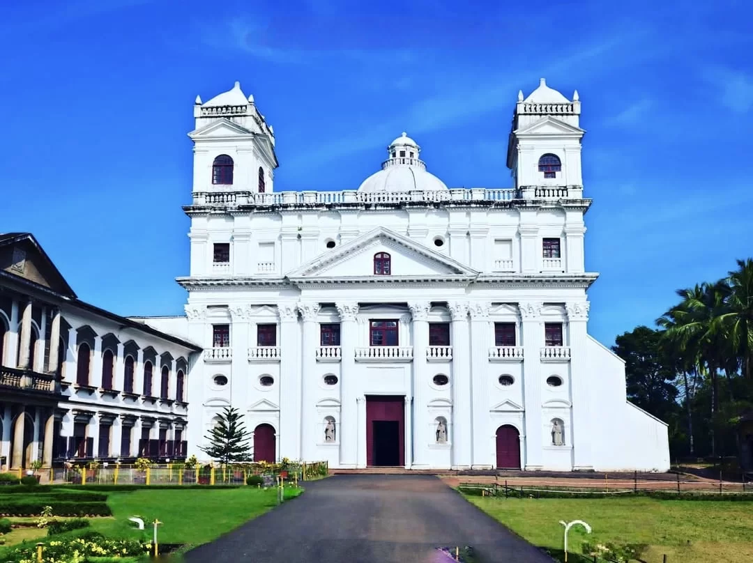 Grand entrance at St Cajetan Church Old Goa during clear skies, featuring ornate towers dome manicured lawns palms, perfect heritage Goa tour package.