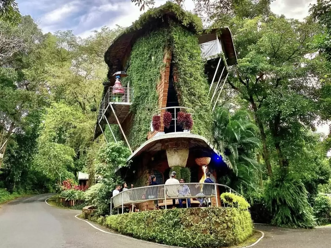 Iconic vine-covered brick house replica at Houses of Goa Museum South Goa, featuring tropical plants balcony visitors greenery path, perfect heritage experience Goa museum tour package.
