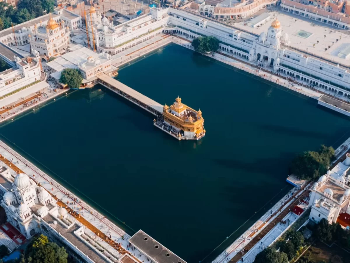 Aerial Golden Temple Amritsar sarovar Harmandir Sahib Akal Takht, golden domes white marble parikrama lush trees, perfect Punjab Sikh pilgrimage aerial package. 