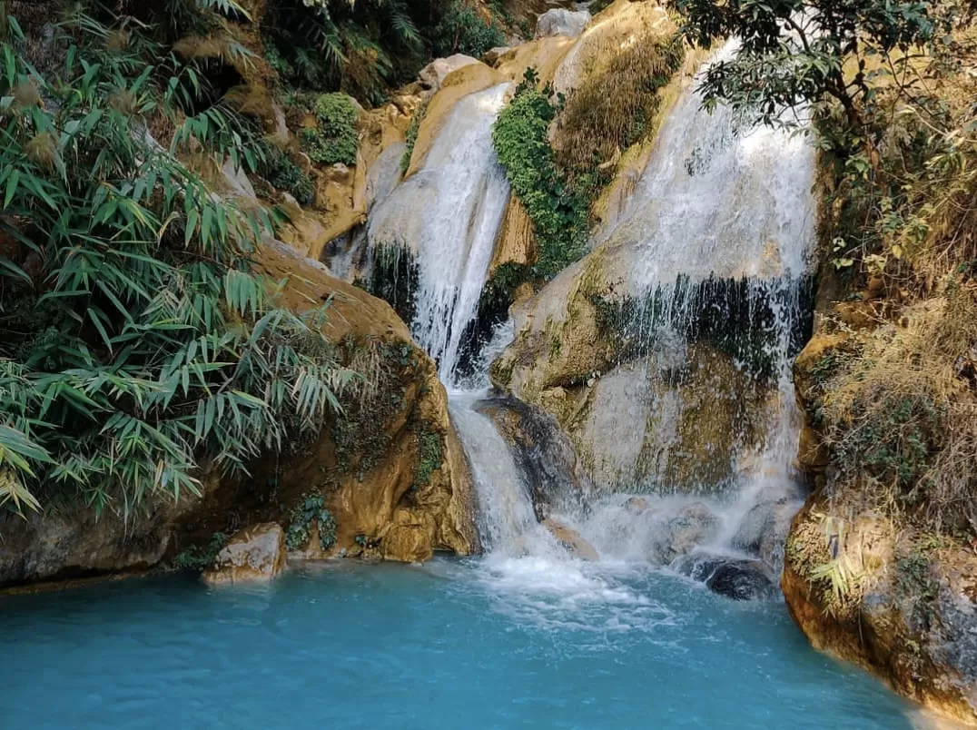 Neer Waterfall at Pachmarhi during sunny day, featuring terraced golden cascades turquoise pool bamboo greenery rocks, perfect adventure experience Pachmarhi tour package.