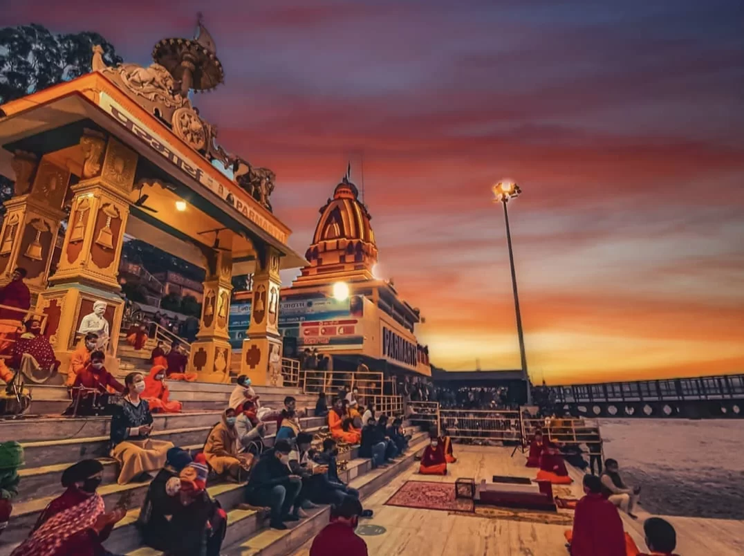 Parmarth Niketan Ashram at Rishikesh during sunset, featuring Ganga aarti saffron-clad sadhus temple ghats lamps, perfect spiritual experience Rishikesh tour package.