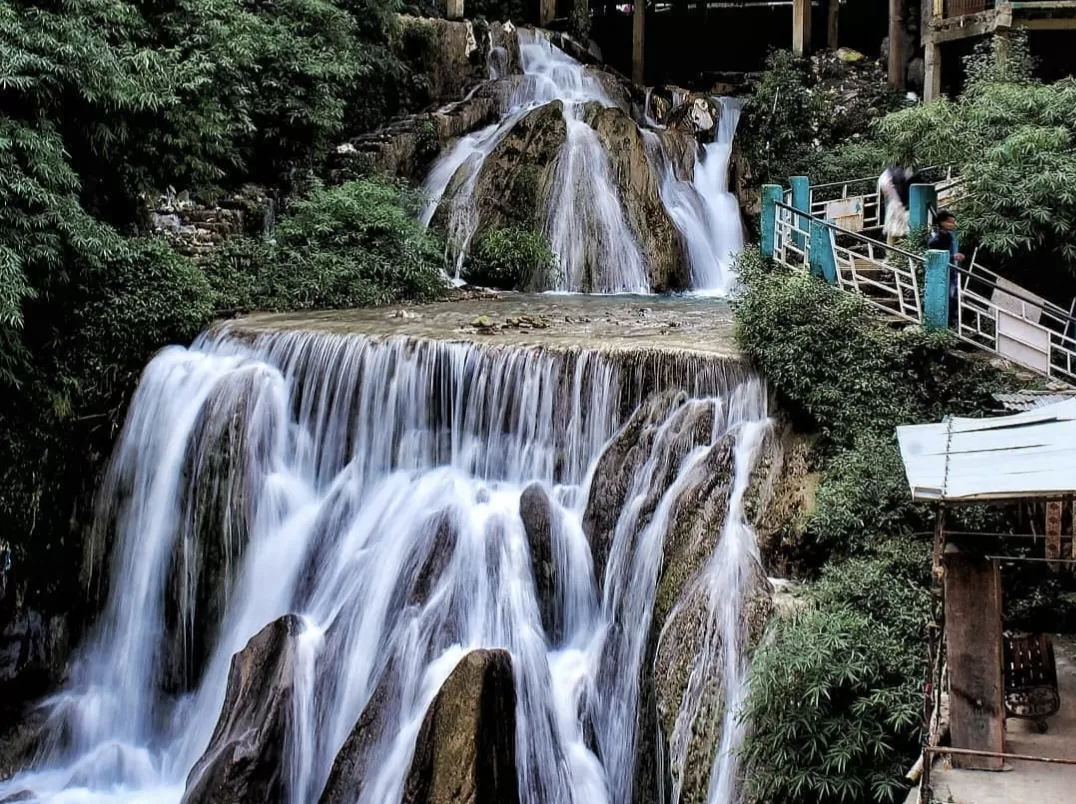 Kempty Falls close-up multi-tiered cascading waterfalls rocky ledges turquoise railings viewing bridge people lush green vegetation backdrop, perfect adventure waterfall visit Uttarakhand tour packages.