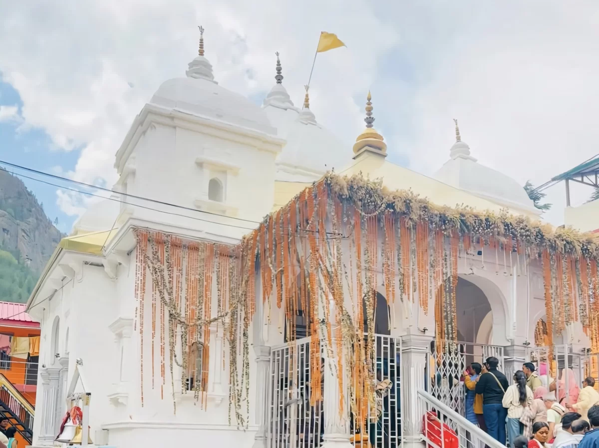 Devotees queue at Gangotri Temple in Uttarkashi during cloudy daytime, featuring white granite shrine and festive garlands, perfect spiritual experience Gangotri tour package.