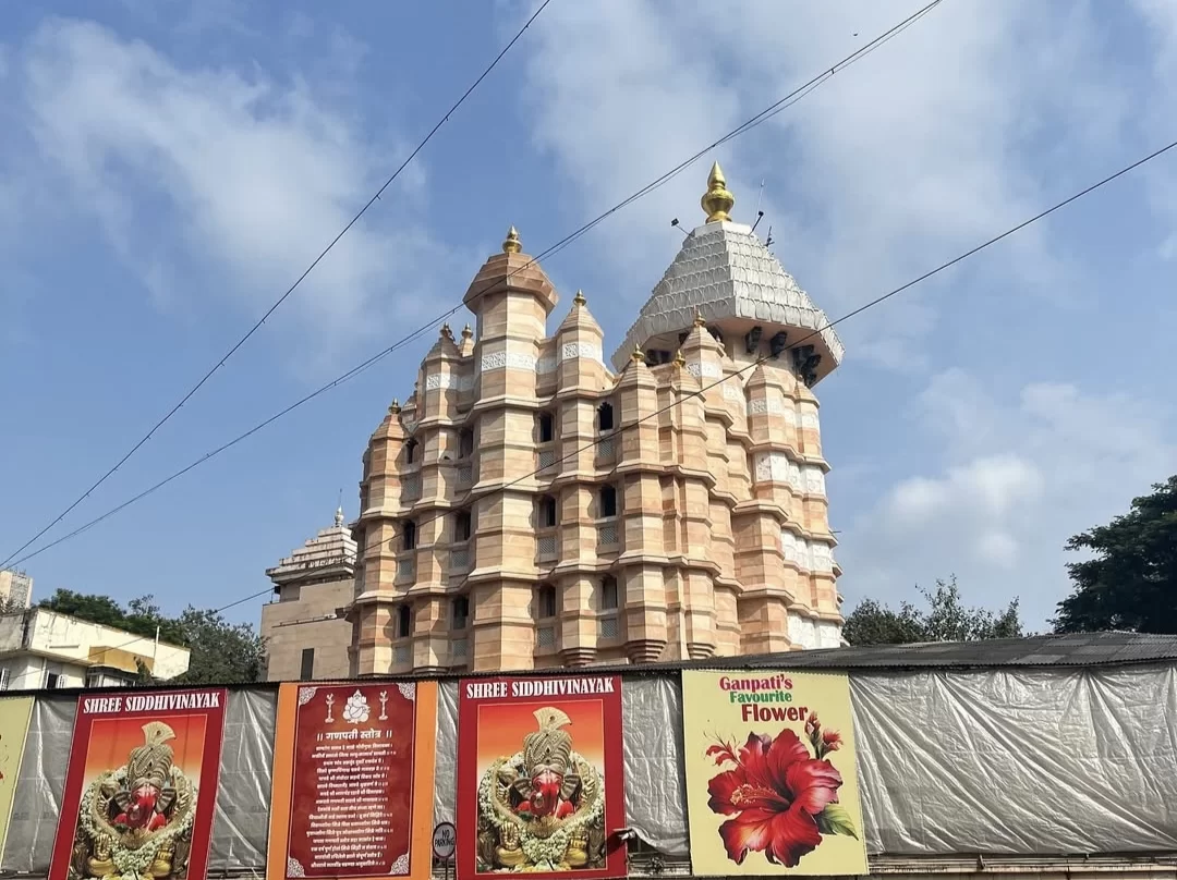 Shri Siddhivinayak Temple Mumbai Prabhadevi multi-tier shikhara banners Ganpati festival hibiscus flowers blue sky, perfect Maharashtra temple heritage tour package.