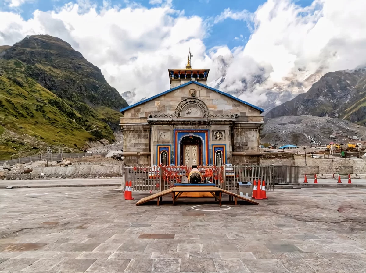 Grand Kedarnath Temple facade at Kedarnath during partly cloudy day, featuring Himalayan peaks saffron barriers ornate doors, perfect spiritual Uttarakhand tour packages.
