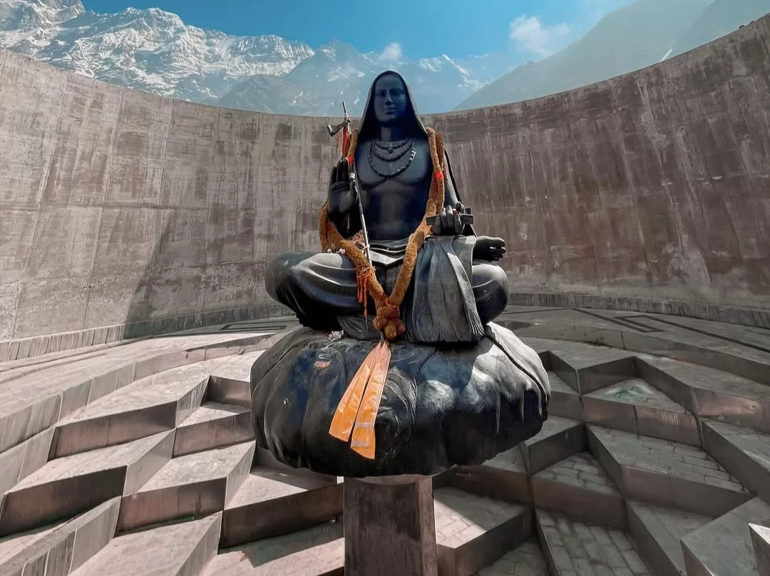 Majestic Neelkanth Shiva statue at Kedarnath during sunny day, featuring trishul garlands snowy peaks concrete amphitheater, perfect spiritual Uttarakhand tour packages.