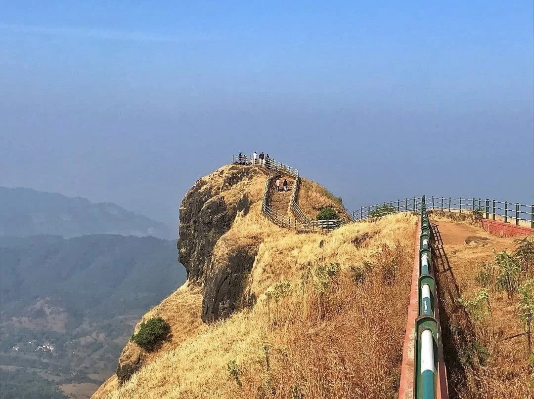 Tourists at summit viewpoint of Lodwick Point Srinagar during clear day, featuring rocky cliffs, grasslands and mountain valleys, perfect adventure experience in Srinagar tour package.