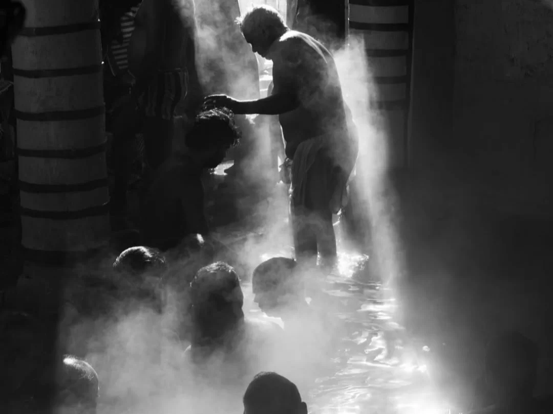 Tapt Kund Badrinath black white pilgrims bathing hot spring steam pillars elderly man pouring water Char Dham spiritual ritual Uttarakhand tour packages.