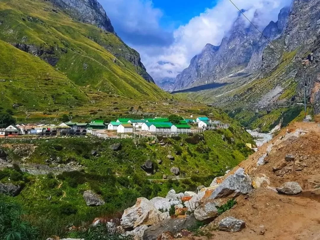 Mana Village Uttarakhand green roof houses terraced fields snowy Himalayan peaks cloudy sky Badrinath last Indian village Uttarakhand tour packages.