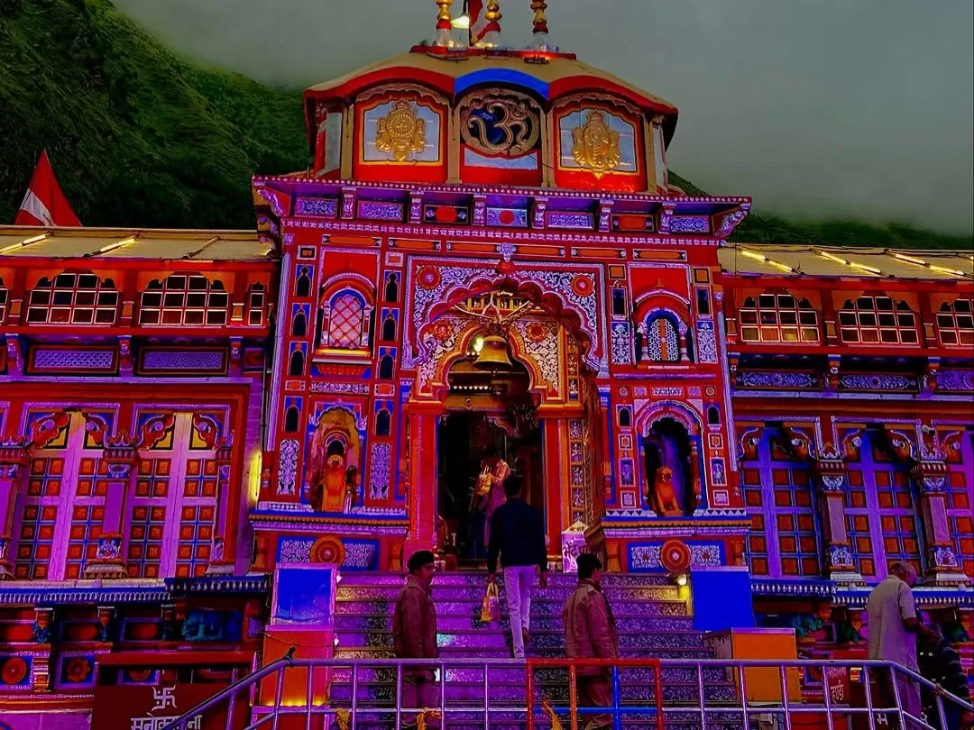 Illuminated Badrinath Temple Uttarakhand at night during misty weather, featuring vibrant architecture and Himalayan peaks, perfect spiritual experience Uttarakhand tour packages.