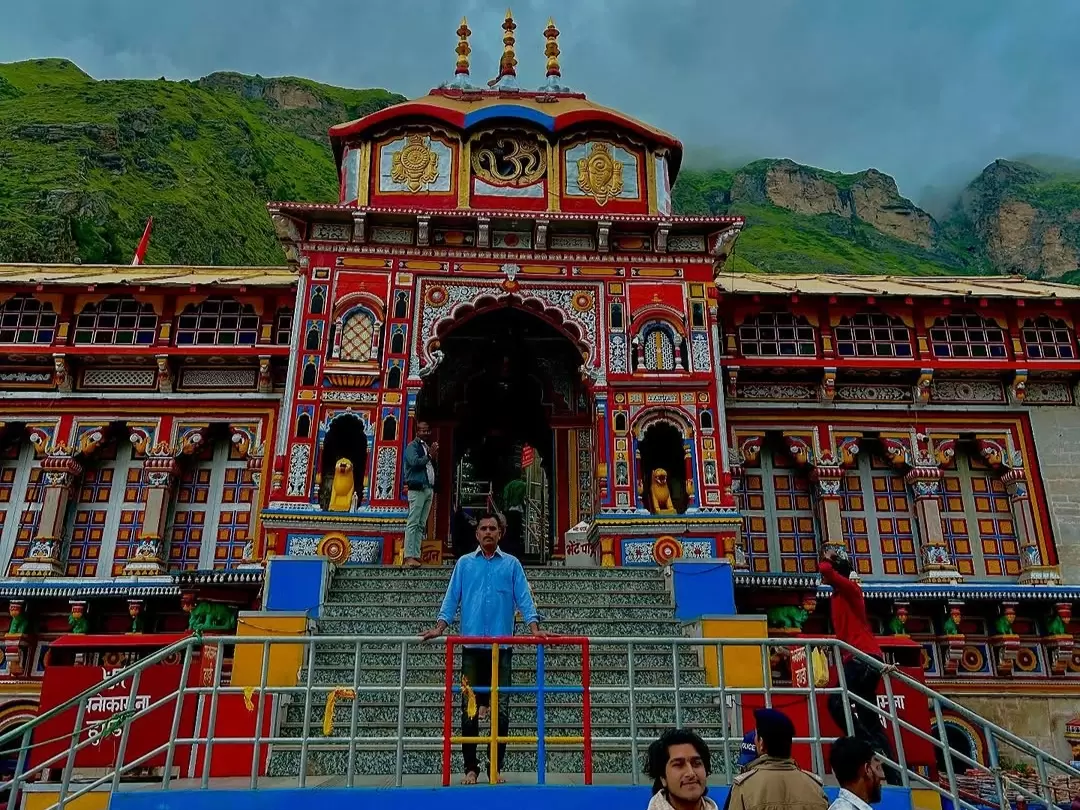 Pilgrim at Badrinath Temple Uttarakhand during cloudy day, featuring ornate architecture and Himalayan mountains, perfect spiritual experience Uttarakhand tour packages.