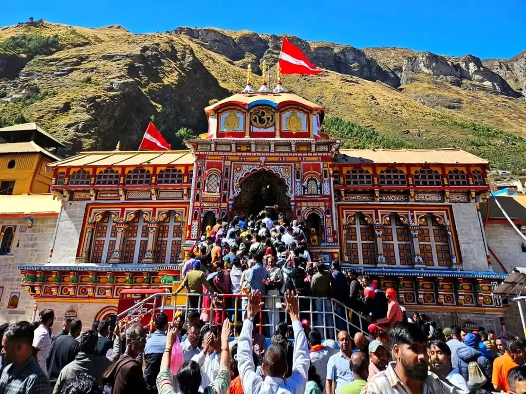 Devotees at Badrinath Temple Uttarakhand during sunny day, featuring colorful architecture and Himalayan mountains, perfect spiritual experience Badrinath tour package.