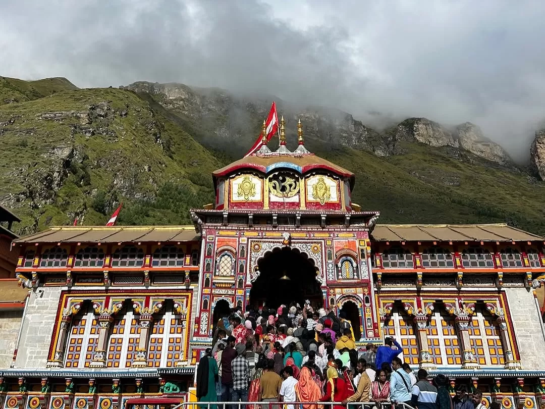 Badrinath Temple Uttarakhand vibrant red gold facade snowy mountains blue sky large pilgrim crowd Char Dham Yatra Uttarakhand tour packages.