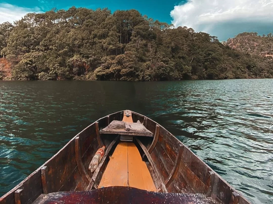 POV rowboat boating at Sattal Lake Nainital during clear daytime, featuring forested hills and blue waters, perfect adventure experience Uttarakhand tour package.