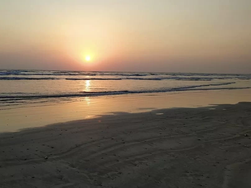 Golden sunset at Varsoli Beach in Alibaug, featuring calm waves and sandy shore reflections, perfect Alibaug tour package