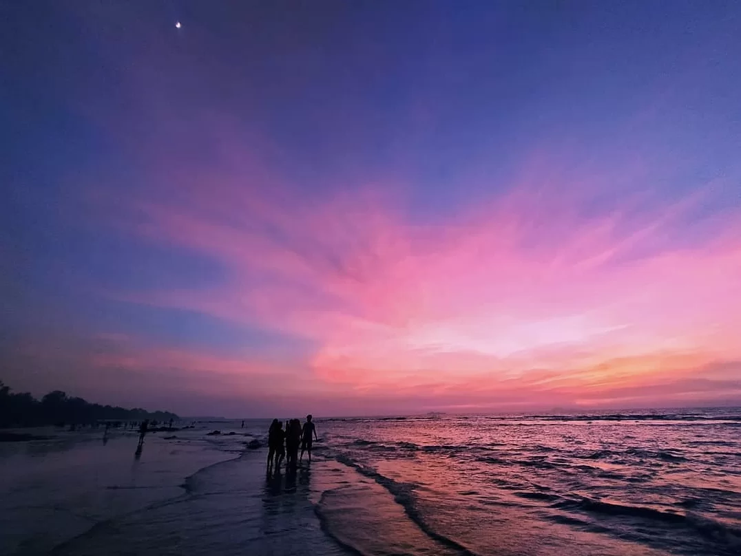 People silhouettes with evening star at Kihim Beach Alibaug during vibrant sunset, featuring pink-purple skies, Arabian Sea waves, perfect romantic Konkan tour package.