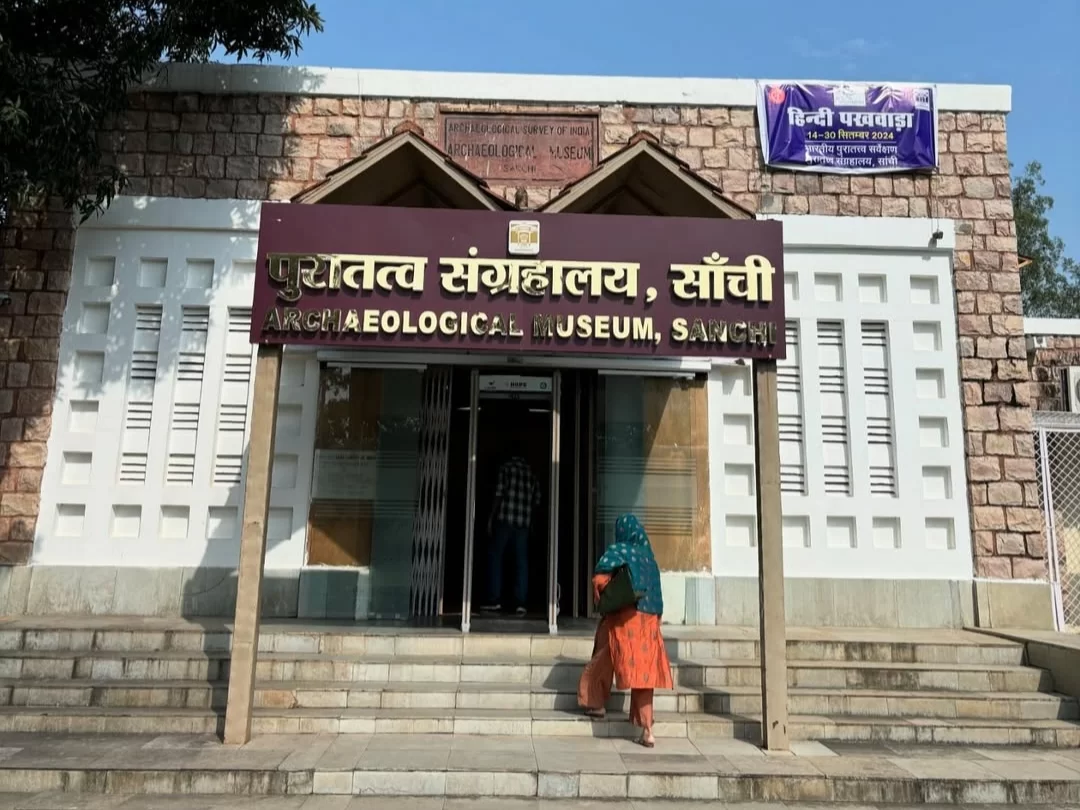 Puratatva Sangrahalaya Archaeological Museum at Sanchi during clear afternoon, featuring bilingual signage and visitors entering, perfect heritage experience in Madhya Pradesh tour package.