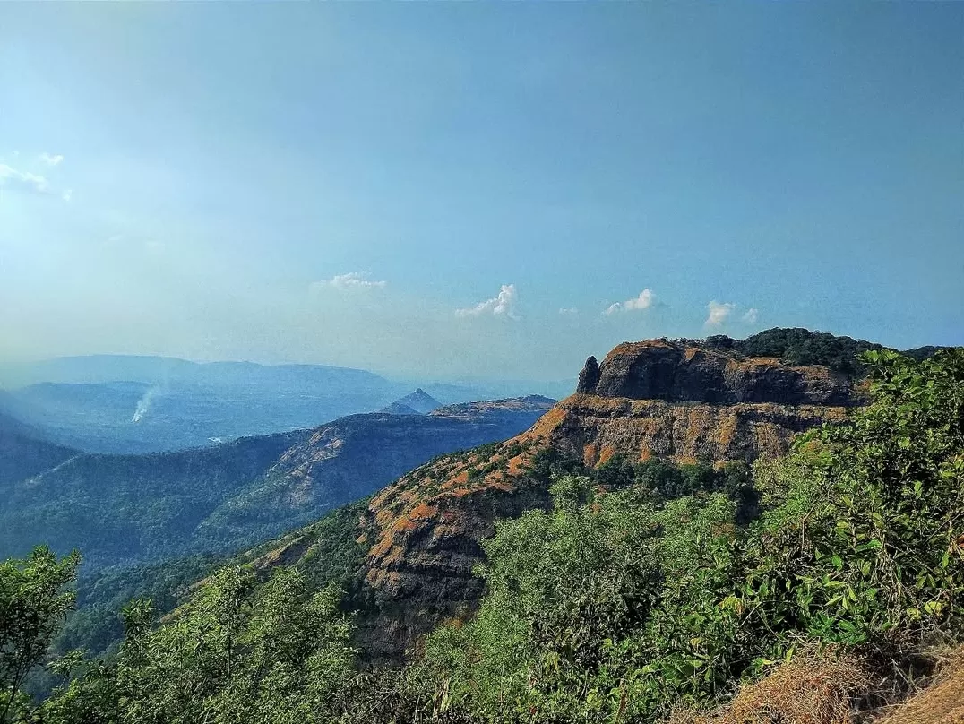 Louisa Point Matheran distant plateau cliffs rocky outcrops green forested valleys hazy blue mountains Western Ghats, perfect Maharashtra hill station expansive viewpoint panorama, Maharashtra tour packages.