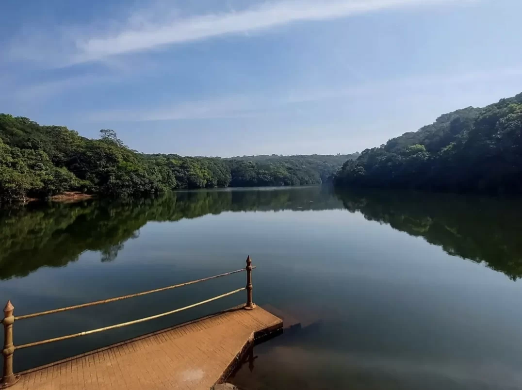 Charlotte Lake at Matheran during clear skies, featuring dense green hills and mirror-like water reflections, perfect adventure experience Maharashtra tour package.