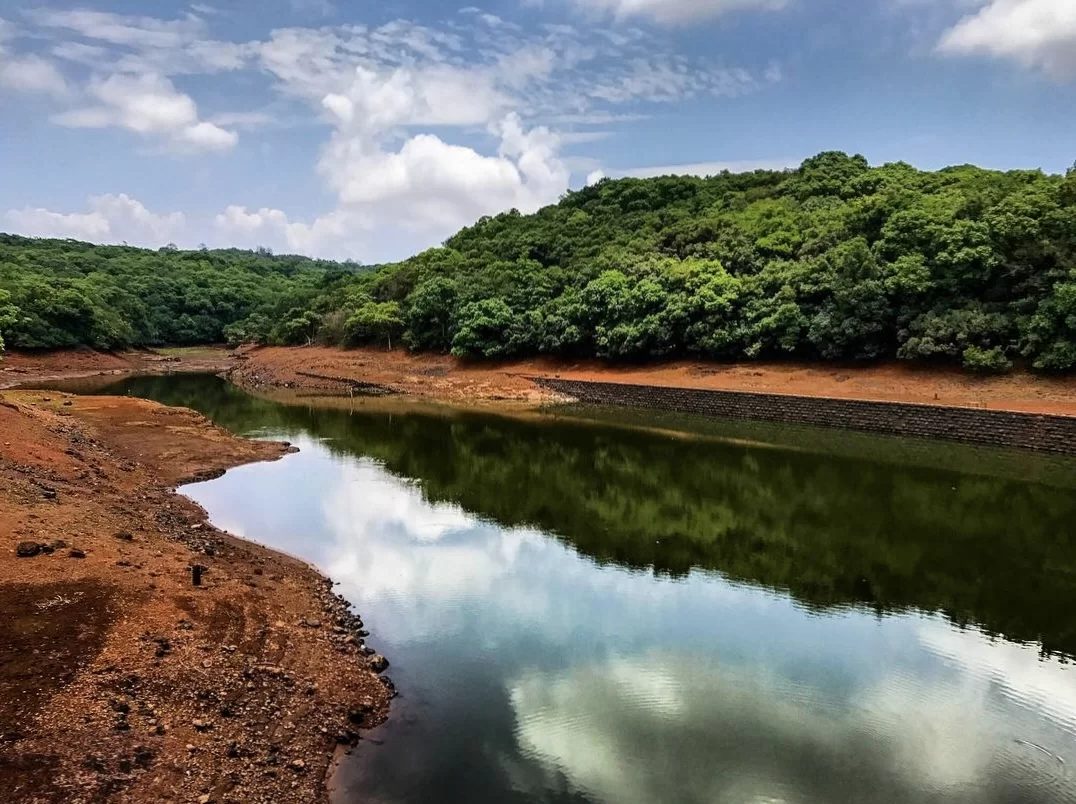 Charlotte Lake at Matheran during clear weather, featuring lush green hills and water reflections, perfect adventure experience Maharashtra tour package.