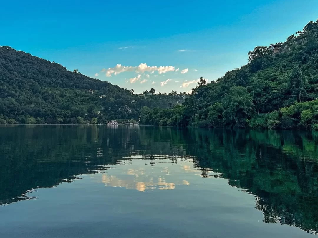 Naukuchiatal Lake Nainital during sunny daytime, featuring emerald waters with perfect mountain reflections and green hills, perfect romantic experience Uttarakhand tour package.