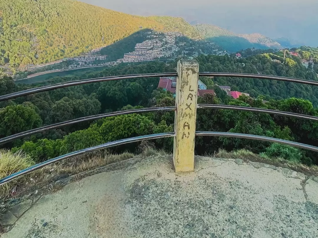 Tiffin Top Nainital yellow signpost Tiffin Top Hindi script amidst curved rusty railings overlooking golden hour pine hills terraced town distant valleys blue hazy skies, perfect Uttarakhand tour packages.