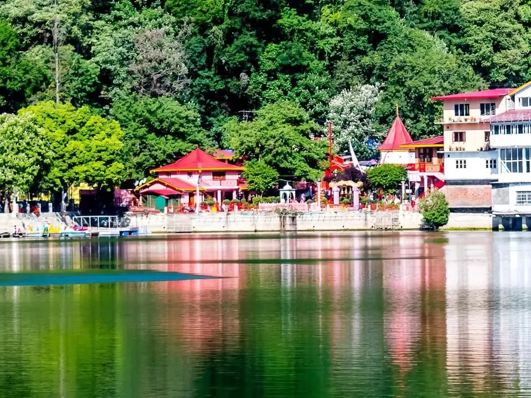 Naina Devi Temple complex along northern shore of Naini Lake Nainital Uttarakhand panoramic view, featuring red-roofed temples amid lush green hills reflected in emerald waters, perfect spiritual heritage landmark hill station tour package.