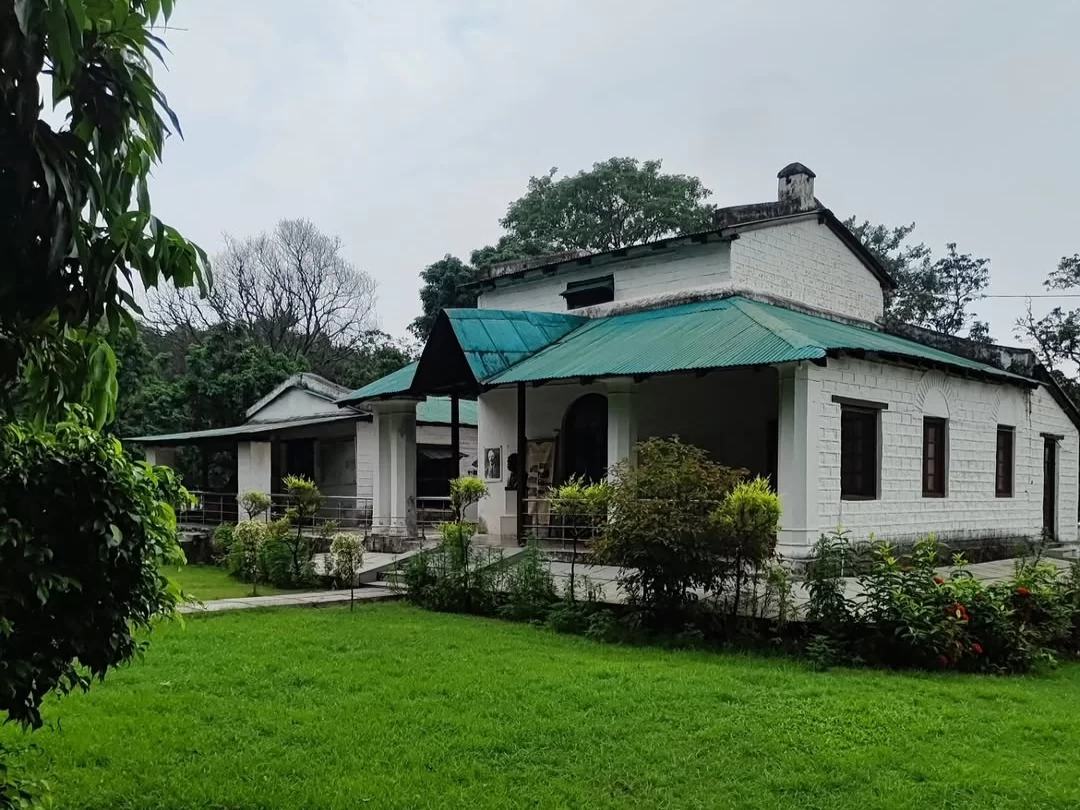 Jim Corbett Museum colonial building green roof white walls garden, heritage house trees cloudy sky potted plants lawn foreground, perfect Uttarakhand tour packages.