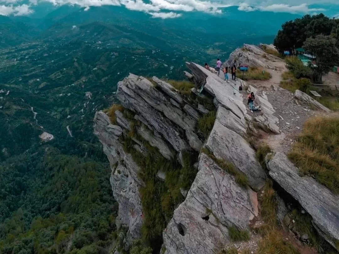 Chauli ki Jali cliff top in Mukteshwar during cloudy weather, featuring tourists trails, deep valleys forests mountains, perfect panoramic trek, Uttarakhand tour packages.