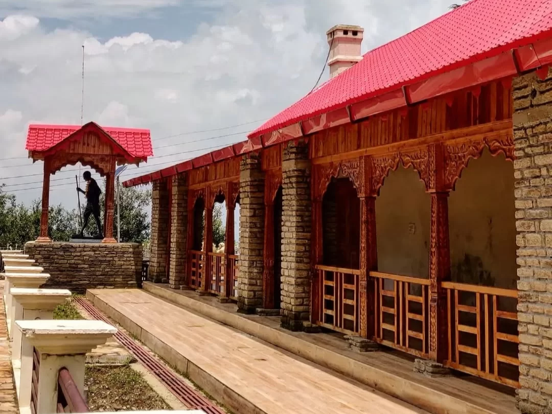 Anasakti Ashram Kausani silhouette Gandhi statue red roof wooden carved pavilion long stone wood veranda mountains blue sky, perfect Gandhi ashram viewpoint, Uttarakhand tour packages.