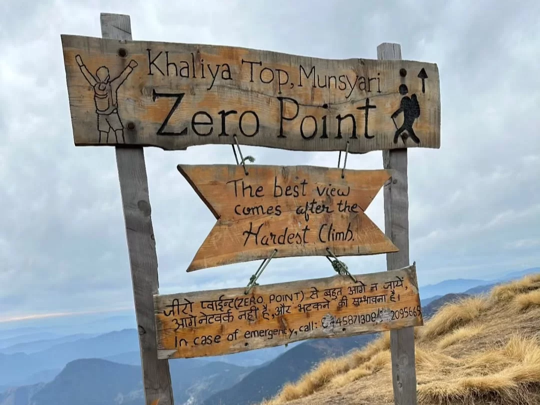 Khaliya Top Munsiyari Zero Point signboard during cloudy weather, featuring trekking info, emergency contact, mountains backdrop, perfect adventure experience, Uttarakhand tour packages.