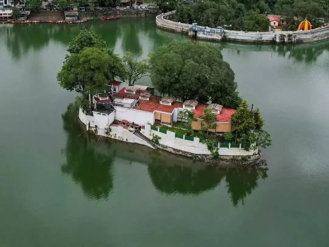 Aquarium Island Cafe Bhimtal aerial view with red white buildings trees walled island on lake boating jetties shoreline, perfect Uttarakhand lake adventure tour packages.