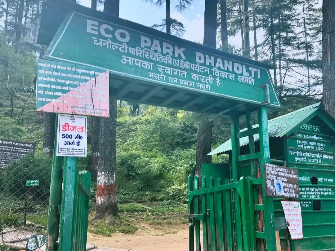 Dhanaulti Eco Park main green entrance gate arch with Hindi signage entry fee 50 rupees amid pine trees featured in Mussoorie Dhanaulti Uttarakhand tour packages