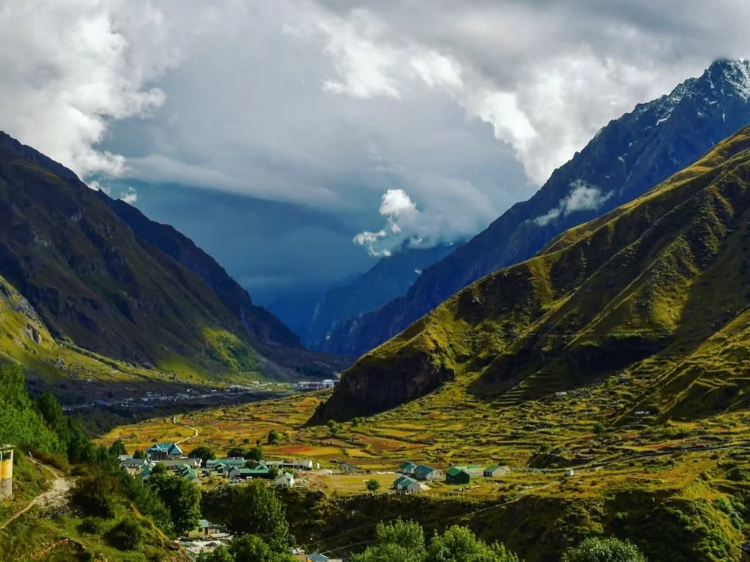 Gurso Bugyal at Auli during cloudy weather, featuring snow-capped mountains green meadows villages, perfect adventure experience Uttarakhand tour packages.