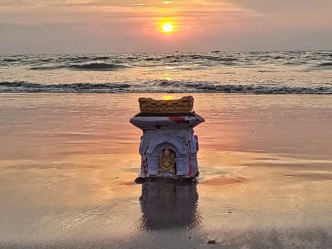 Majorda Beach Goa sunset idol shrine golden sands waves reflection, purple pedestal sun horizon serene waters, perfect South Goa spiritual beach tranquility package. 