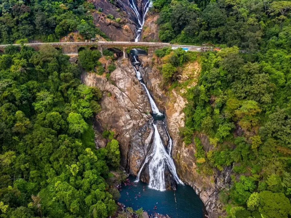 Dudhsagar Waterfall Goa aerial road bridge misty twin cascades lush forests, white streams rocky cliffs turquoise pool Western Ghats, perfect Goa Sanguem waterfall package.