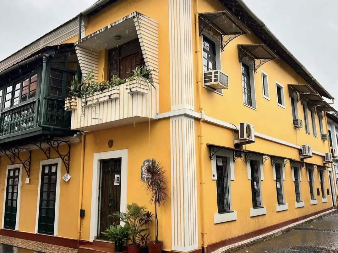 Vibrant red Portuguese heritage house in Fontainhas Latin Quarter Panaji Goa, featuring white trim verandas plants blue sky, perfect heritage experience Goa heritage walking tour package.